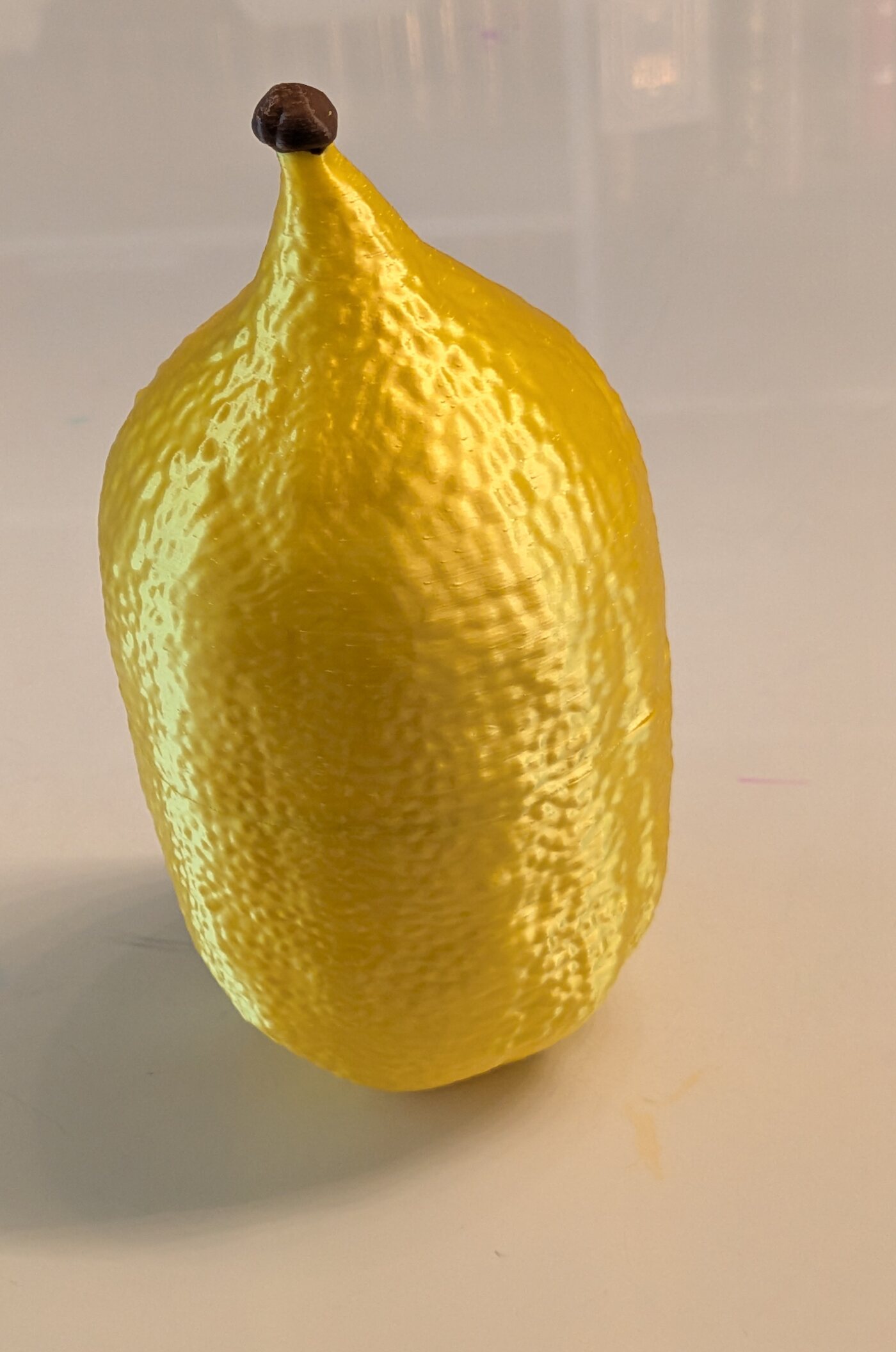 A 3D-printed etrog case, closed, resembling a real citron with its stem intact.